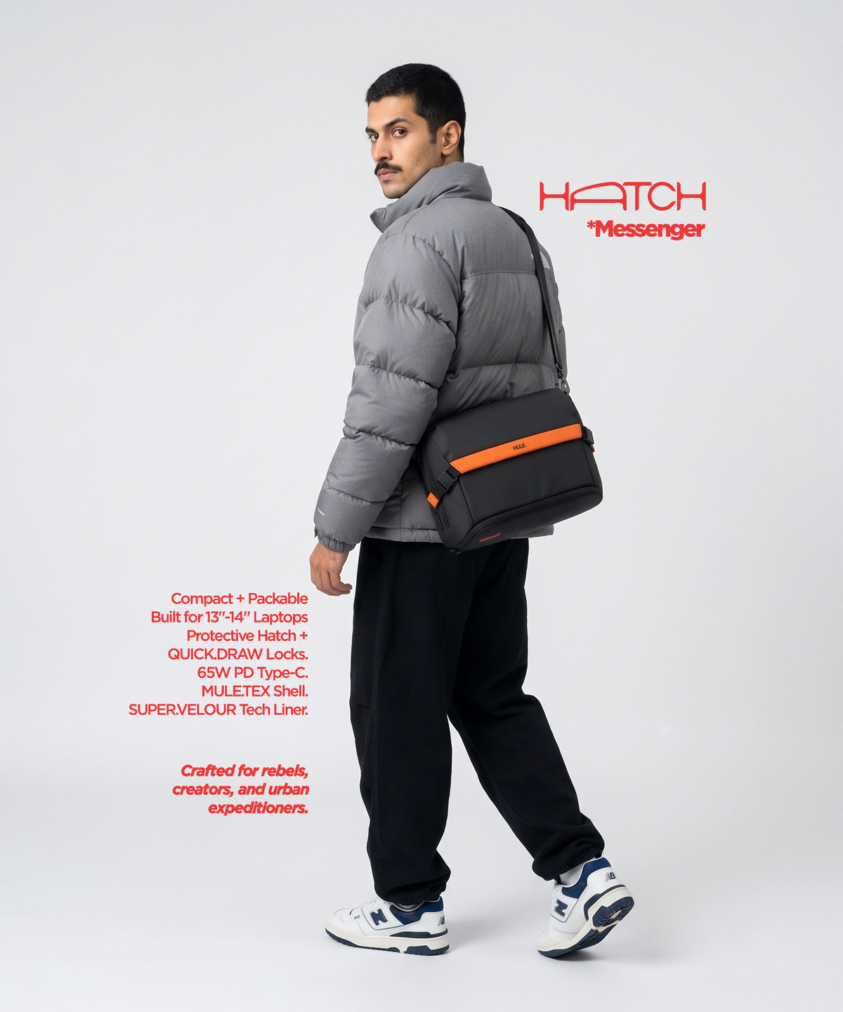 A model wearing a Mule hatch messenger bag with orange accents and a black strap, styled over a cream graphic t-shirt and blue jeans against a solid beige background.