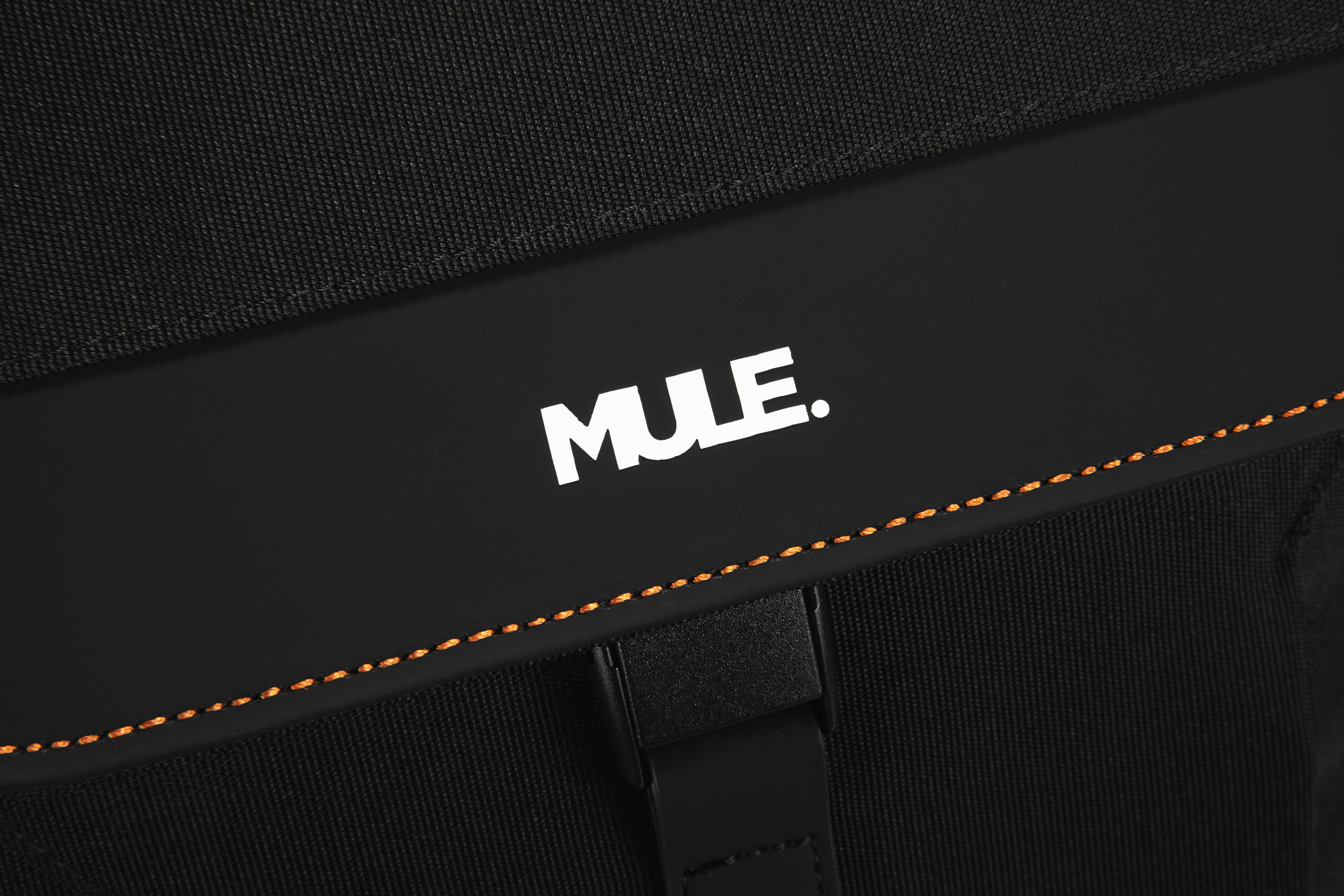 Close-up of a black bag with 'MULE.' logo and orange stitching detail.